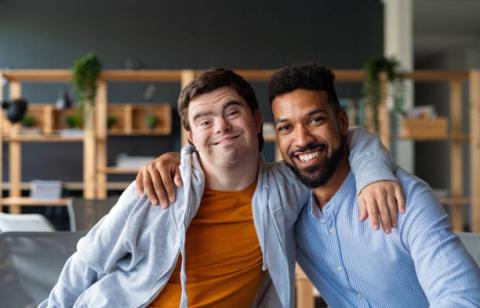 Image of student with adult, arm-in-arm. Both are smiling and facing the camera.