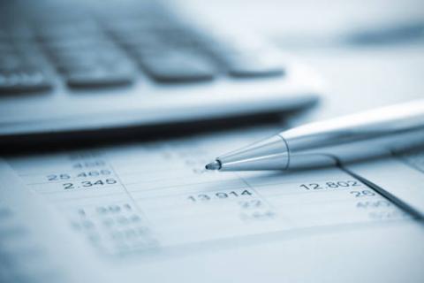 Image of a pen near a calculator and financial report. 